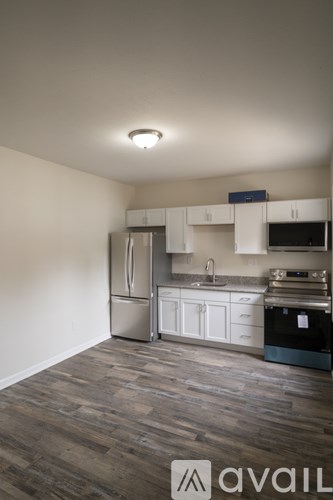 A kitchen with a refrigerator, sink, and cabinets.