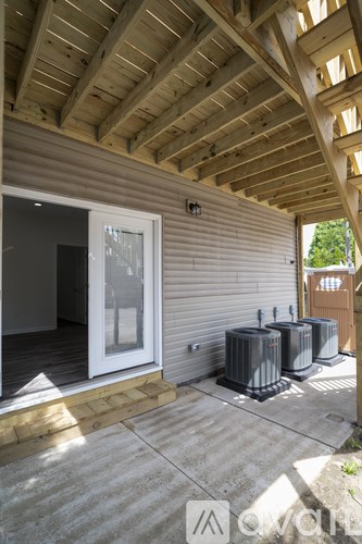 A wooden porch with a sliding glass door and three air conditioning units.