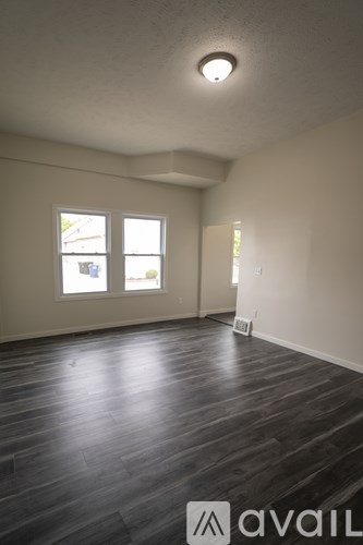 A room with wooden floors and two windows.