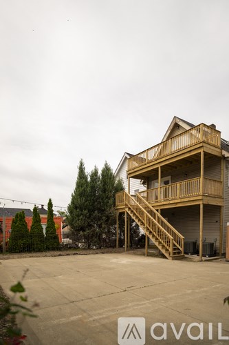 A wooden two-story house with a balcony and stairs.