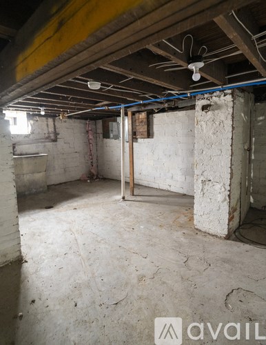 A room with a concrete floor and walls, a ceiling fan, and a door in the middle.
