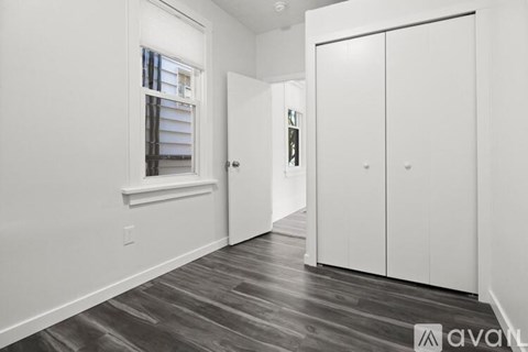 A room with a window and a wooden floor.