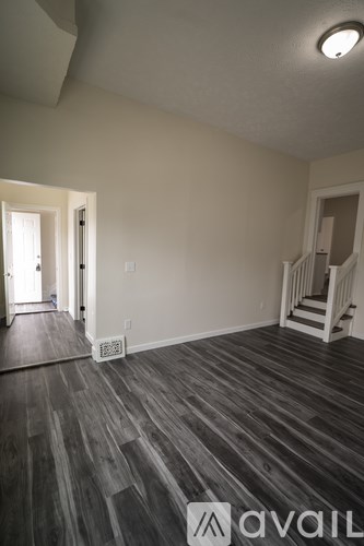 A room with wooden flooring and a staircase.