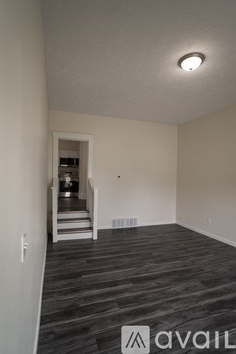 A room with wooden flooring and a staircase leading to another room.