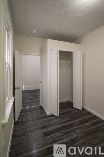 A hallway with a wooden floor and white walls.
