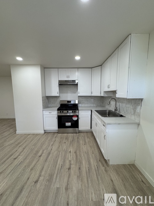 A kitchen with white cabinets and a wooden floor.