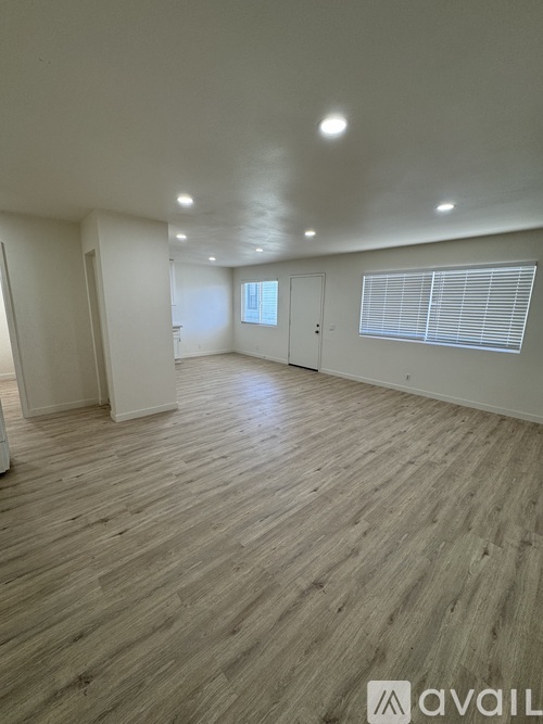 A spacious room with wooden flooring and white walls.