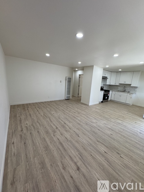 A spacious room with wooden flooring and white walls.