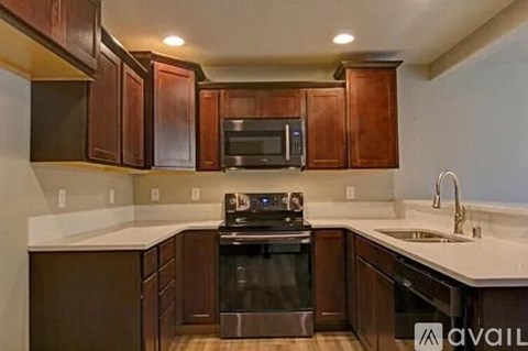 A kitchen with dark wood cabinets and stainless steel appliances.