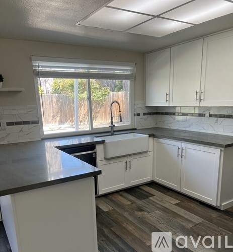 A kitchen with white cabinets and a black countertop.