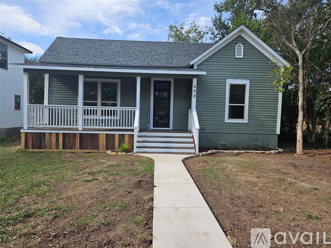 A small house with a porch and a walkway leading to the front door.
