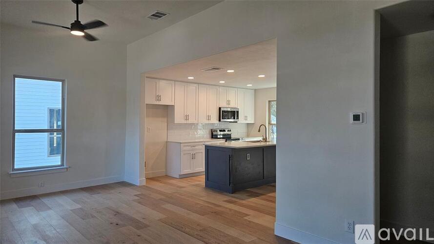 A modern kitchen with white cabinets and a wooden floor.