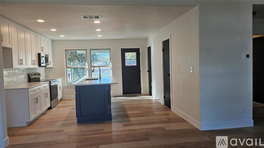 A kitchen with white cabinets and a black island.