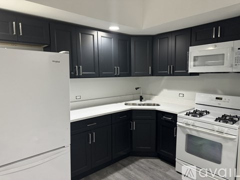 A kitchen with black cabinets and white appliances.