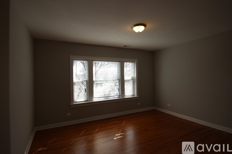 A room with a window and wooden floors is available for rent.