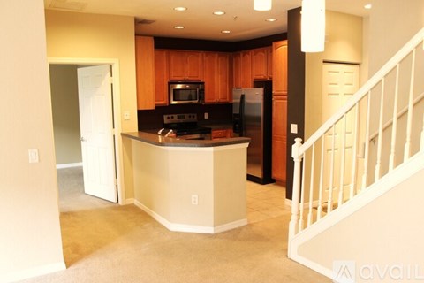 A kitchen with wooden cabinets and a white staircase.