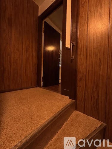 A dark wooden door with a handle and a step leading up to it.
