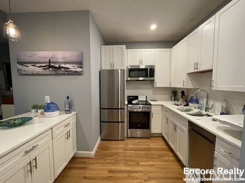A kitchen with white cabinets and a wooden floor.