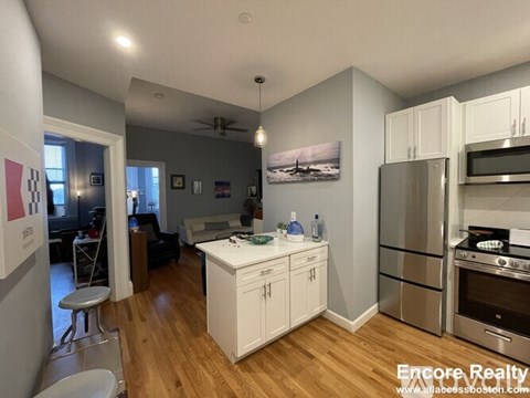 A kitchen with white cabinets and a wooden floor.