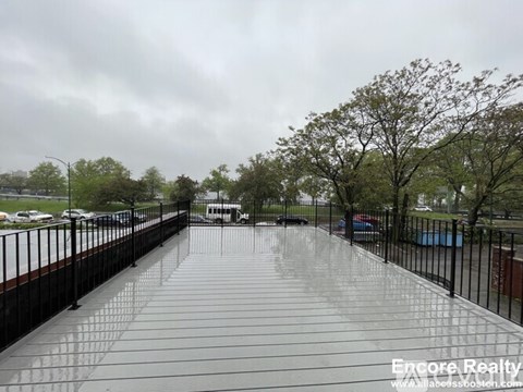A wet walkway leads to a building with trees on either side.
