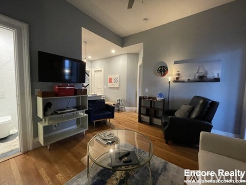 A modern living room with a glass coffee table and a black leather chair.