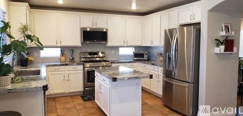A kitchen with white cabinets and a stainless steel refrigerator.