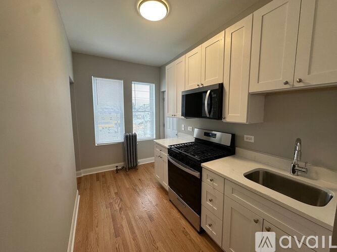 A kitchen with wooden floors and white cabinets.