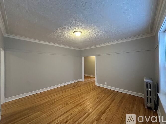 A room with wooden flooring and a window on the right side.