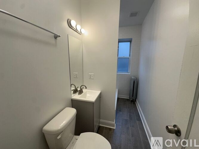 A bathroom with a toilet, sink, and mirror.