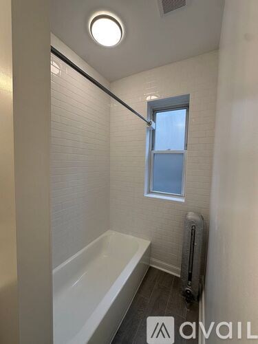 A small bathroom with a white tub and a window.