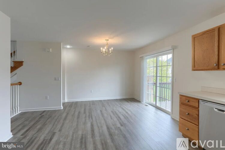 A spacious room with wooden flooring and a chandelier hanging from the ceiling.