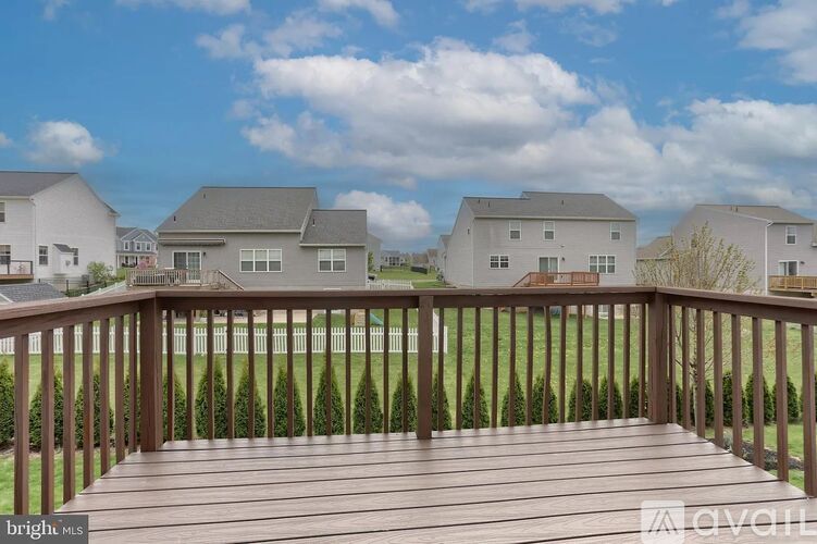 A wooden deck overlooks a grassy area with houses in the background.