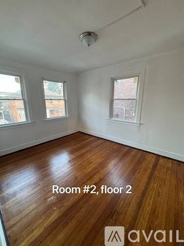 A room with wooden floors and two windows on the second floor.