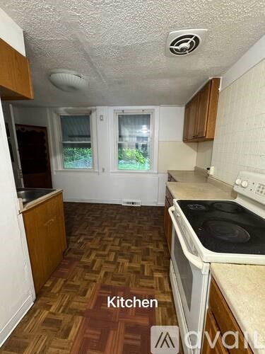 A kitchen with a white stove top oven and wooden cabinets.