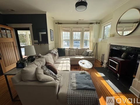 A living room with a grey couch and a fireplace.