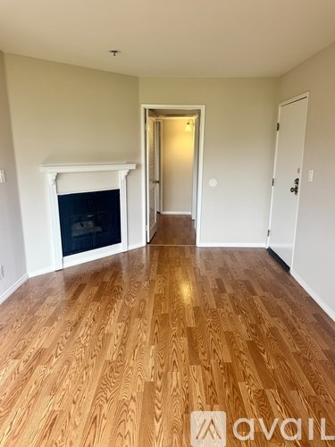 A room with wooden flooring and a fireplace.