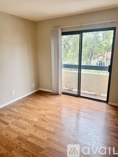 A room with wooden flooring and a sliding glass door.