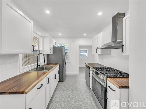 A modern kitchen with white cabinets and a wooden countertop.