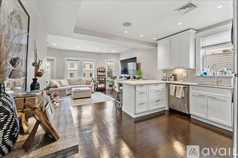 A modern kitchen with white cabinets and a wooden floor.
