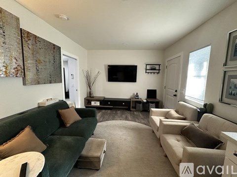 A living room with a green couch and a television mounted on the wall.