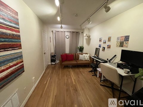 A living room with a couch, a television, a desk, and a painting on the wall.
