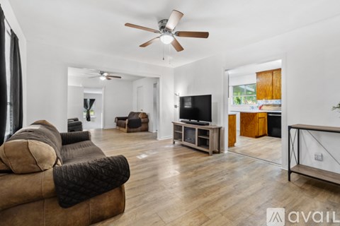 A living room with a brown couch and a ceiling fan.