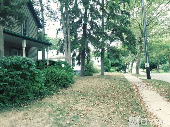 A house with a green lawn and trees in front of it.