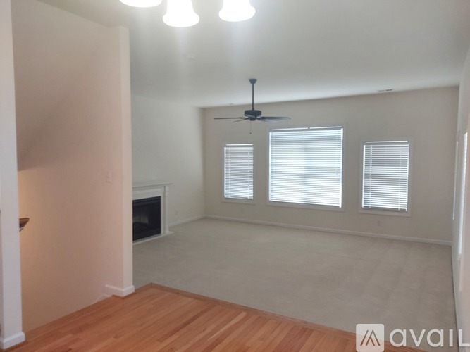 A room with a fireplace, a fan, and a window with blinds.