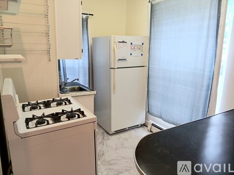 A kitchen with a white fridge, a white gas stove, and a black counter.