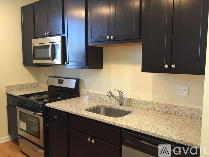 A kitchen with black cabinets and a granite countertop.