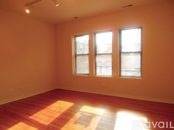 A room with wooden flooring and two windows.