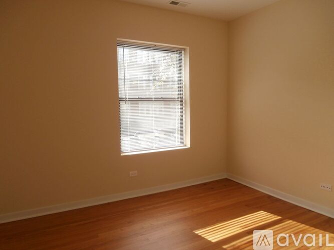 A room with wooden floors and a window with blinds.