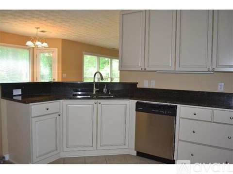 A kitchen with white cabinets and a black countertop.