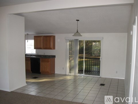 A kitchen with a black dishwasher and wooden cabinets.